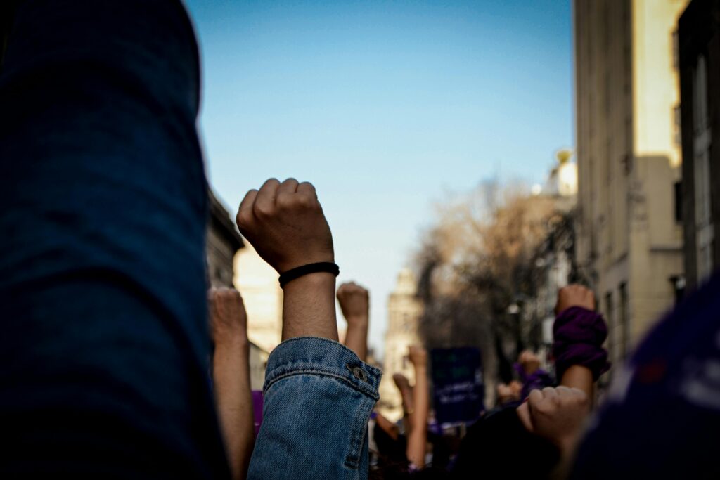Vivid scene of women raising fists at an outdoor rally, symbolizing empowerment and rights advocacy.
