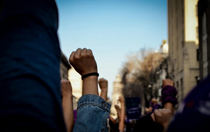 Vivid scene of women raising fists at an outdoor rally, symbolizing empowerment and rights advocacy.